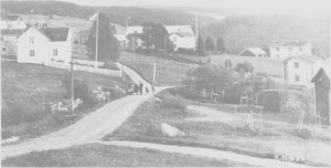 Ås sentrum med Åsheim (til venstre), Bønsgarden, Forbruksforeninga og Klokkargarden. Vi skimter deler av Østbygrenda bak huset på Åsheim. I sentrumsområdet Ås - Østby gikk folketallet ned etter 1900.
